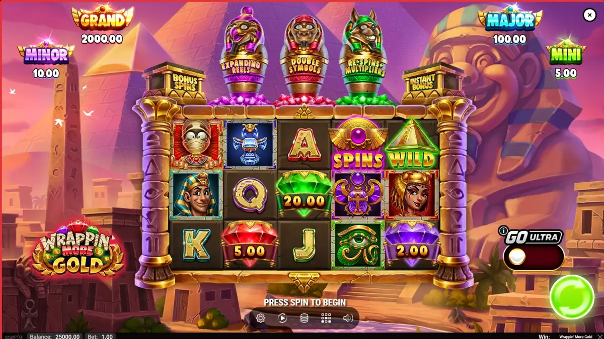 Tampilan antarmuka seluler slot Wrappin’ More Gold dengan mumi ramah dan gulungan penuh permata.